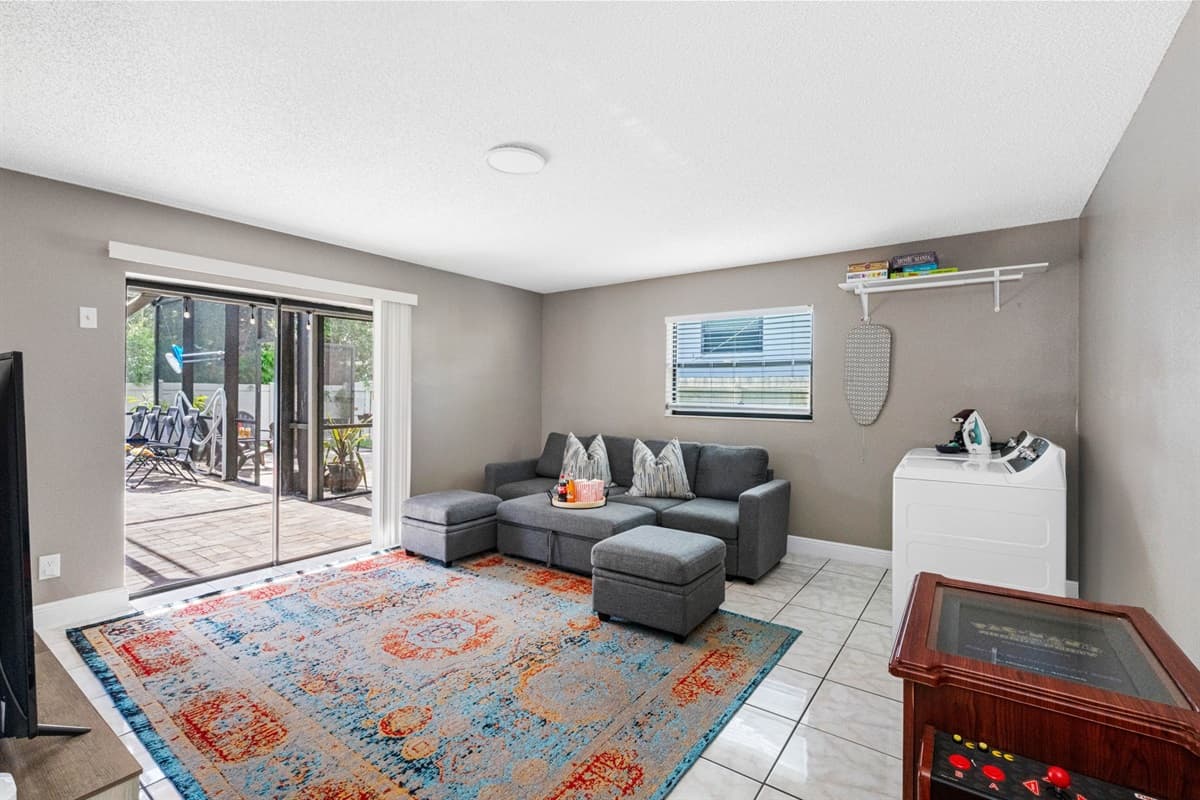 The room is bright and airy, thanks to a wide glass sliding door that leads directly to a screened patio—making indoor-outdoor living seamless.