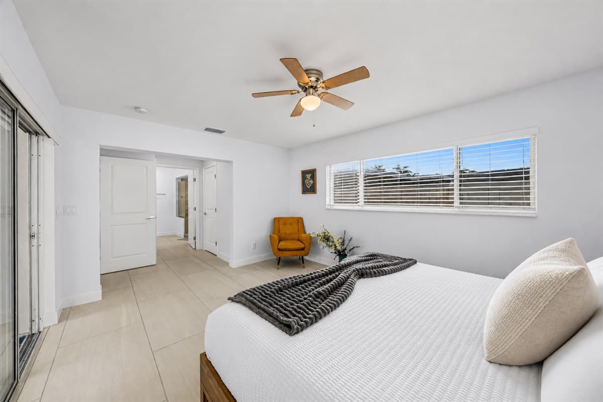 Spacious bedroom retreat with minimalist design, ceiling fan, and calming neutral tones.