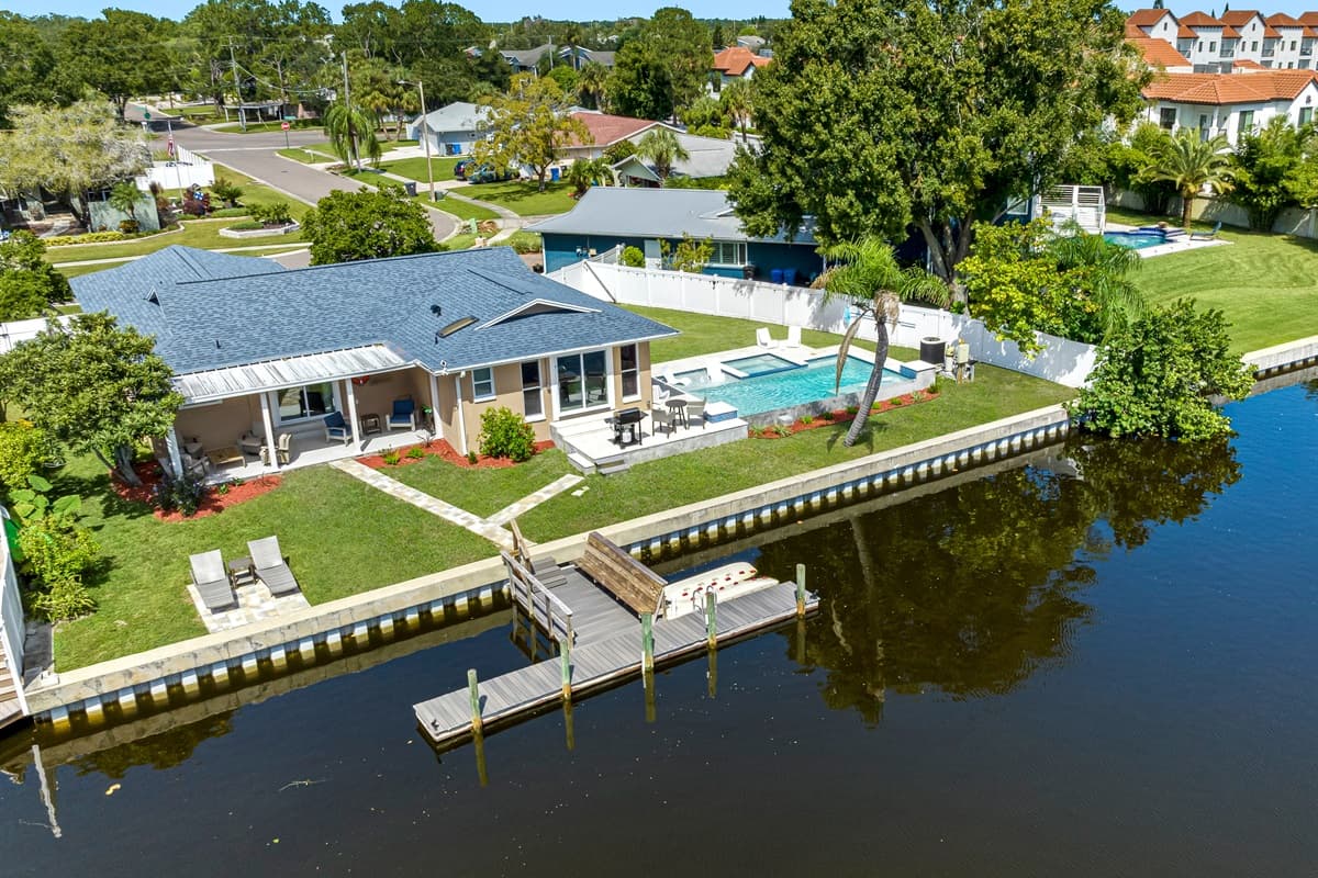 Aerial back view of the property showcasing the immaculate heated pool and access to dock in the lake. Don't hesitate to send us a message!