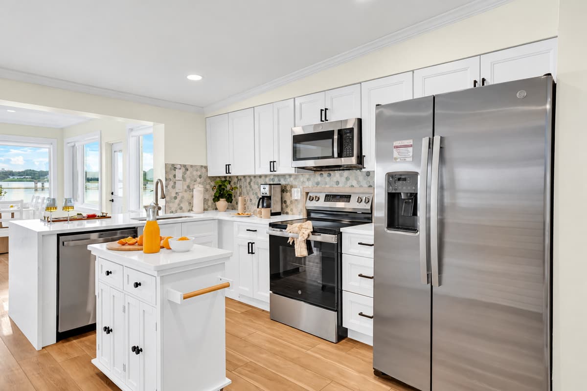 A kitchen with a view of the bay. The kitchen opens toward the waterfront windows. Cook breakfast while you watch the light on the water.