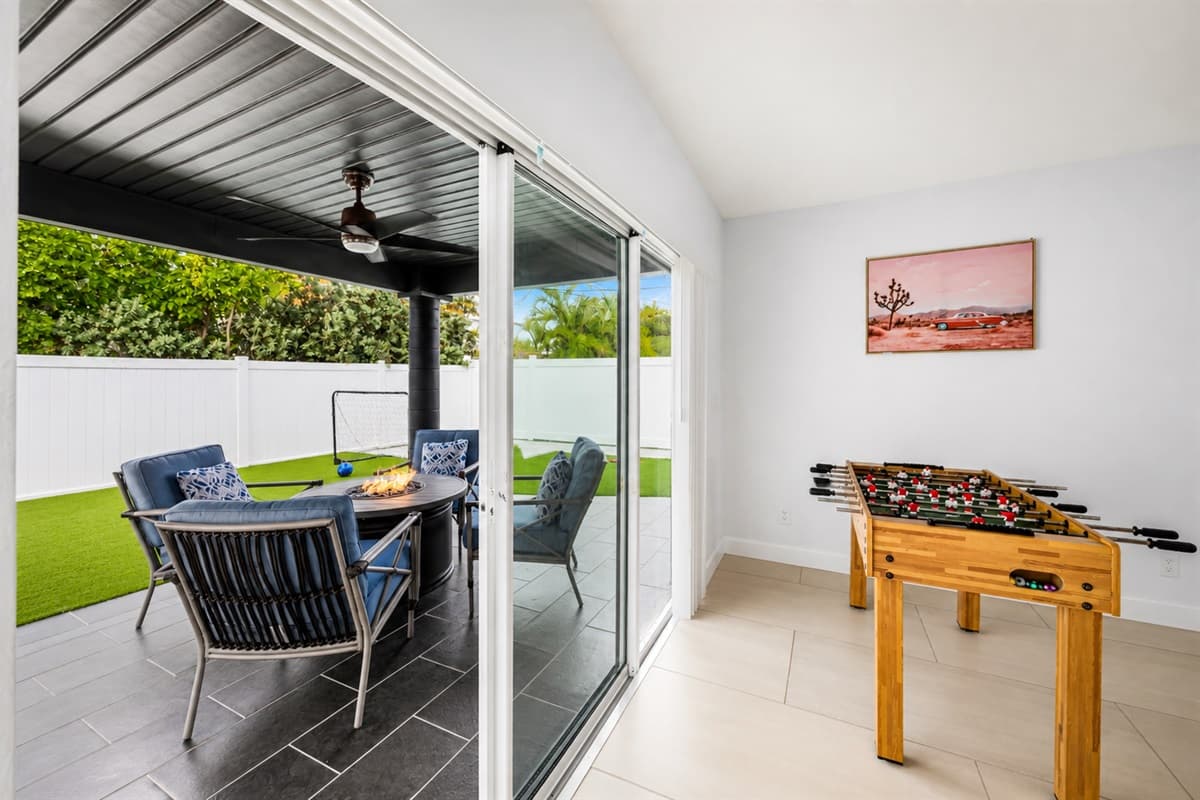 Indoor-outdoor living space with patio access, foosball table, and comfortable lounge seating.

