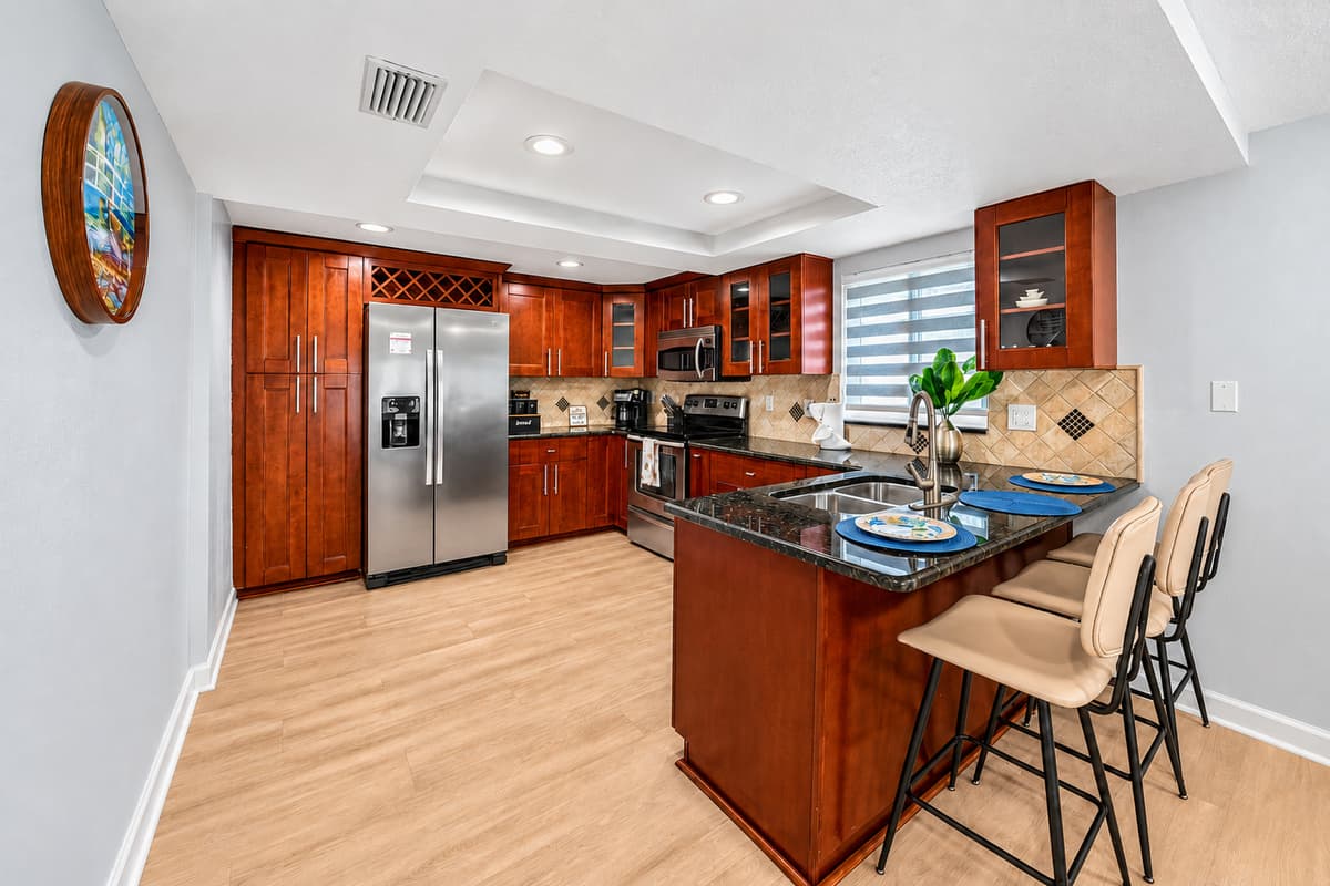 Fully equipped kitchen with stainless steel appliances, granite countertops, a breakfast bar, and ample space for preparing meals during your stay.