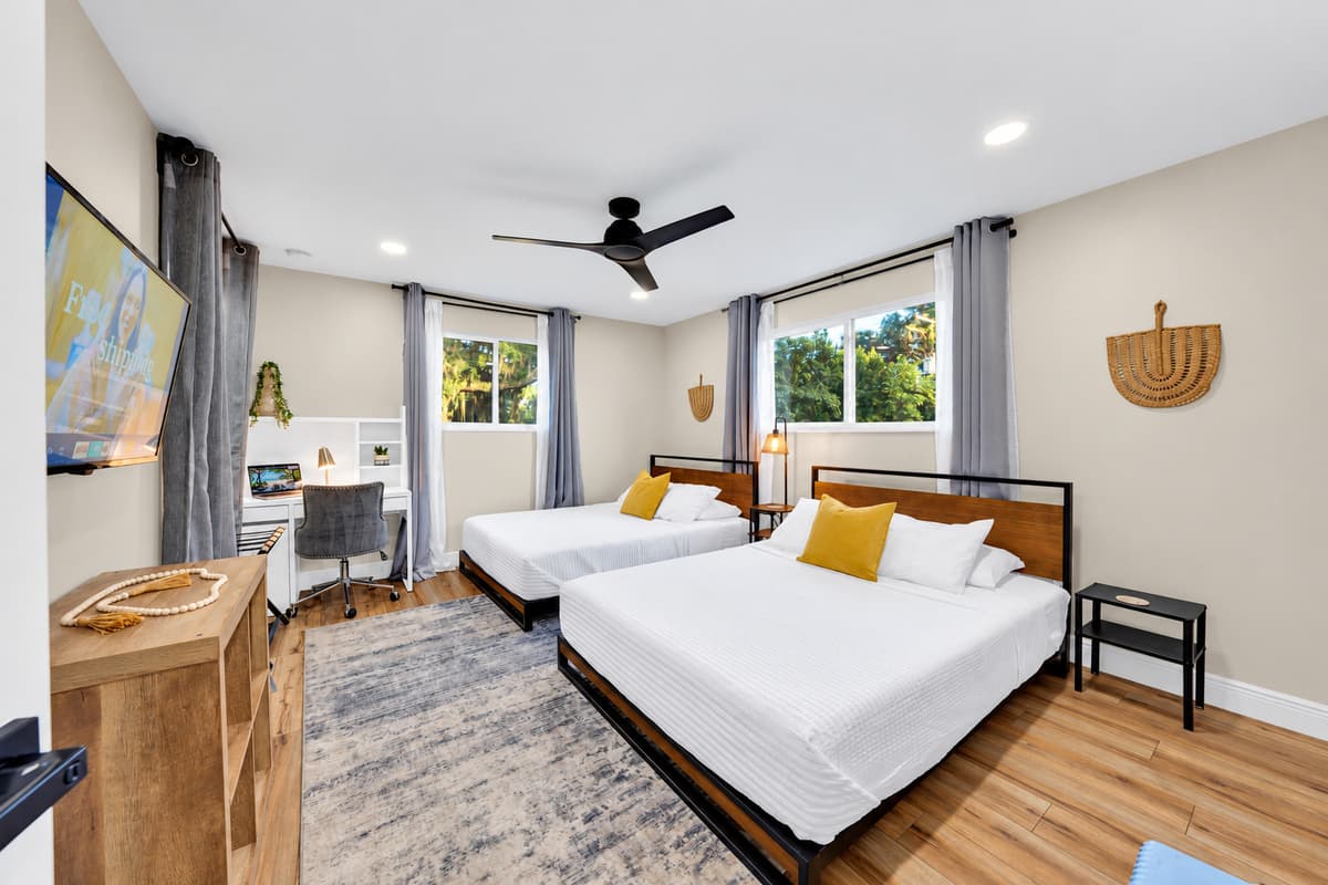 The room that solves the sleeping arrangement. Two full queen beds, generous storage and daylight from the window, with enough floor space that four people unpack without colliding.
