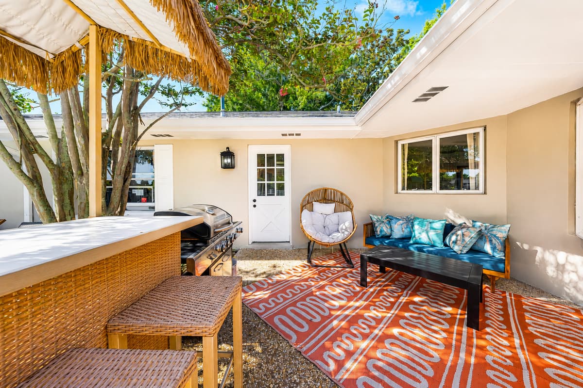 Shade from a real tree, a table for six, and a sofa for after. Florida heat handled without going inside.