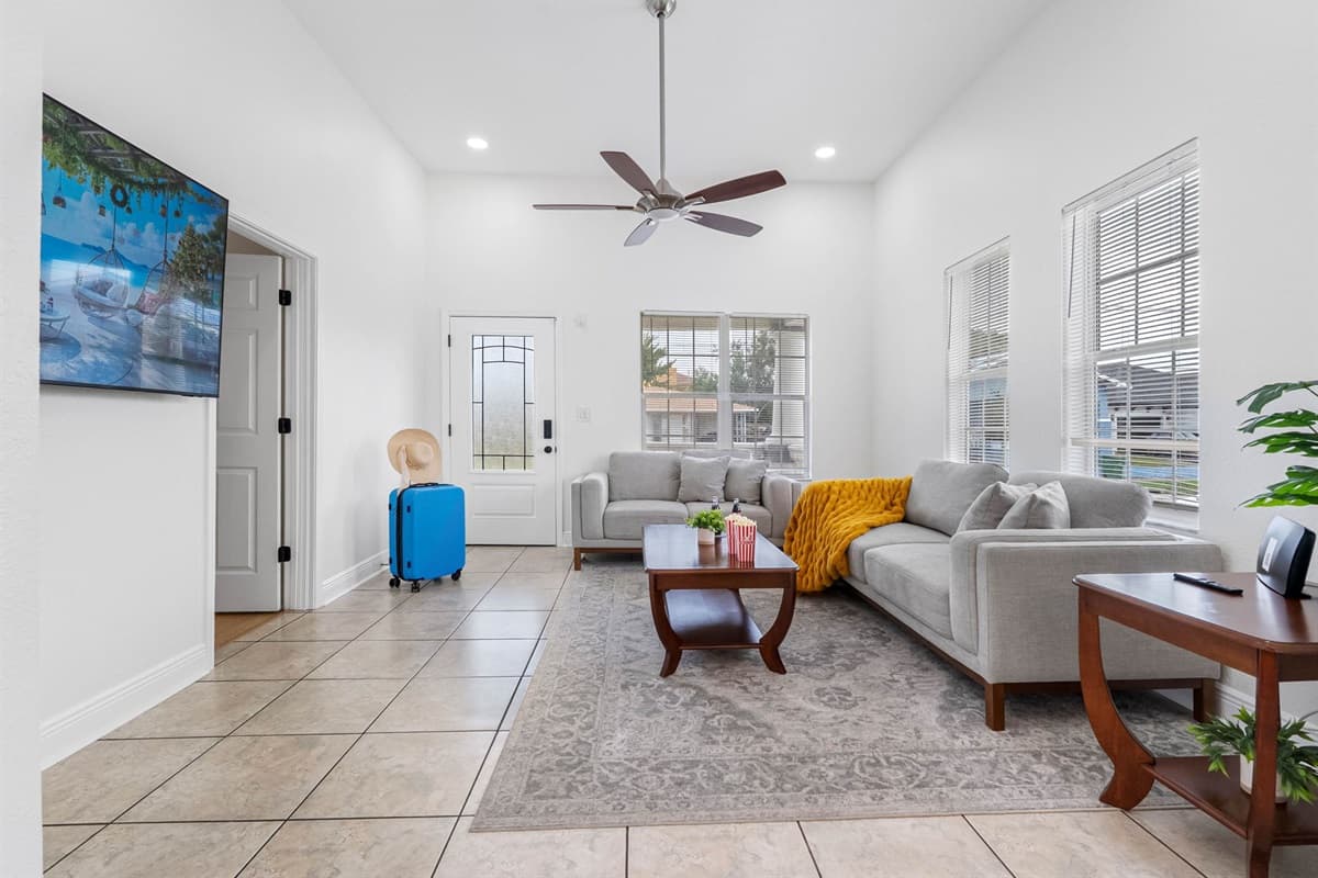 This open and airy living room boasts high ceilings, large windows, and comfortable furniture, making it a perfect spot to relax and socialize.