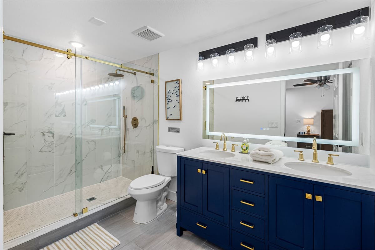 Bedroom 1 - Ensuite: This bathroom boasts a sleek navy double vanity, gold fixtures, and a walk-in glass shower that feels like a 5-star hotel.