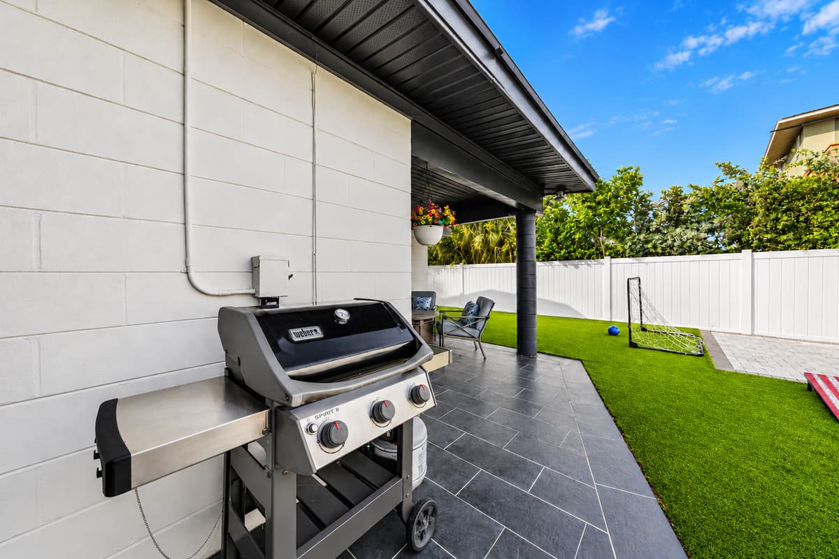 Gas grill setup conveniently located beside the covered patio and backyard lawn.