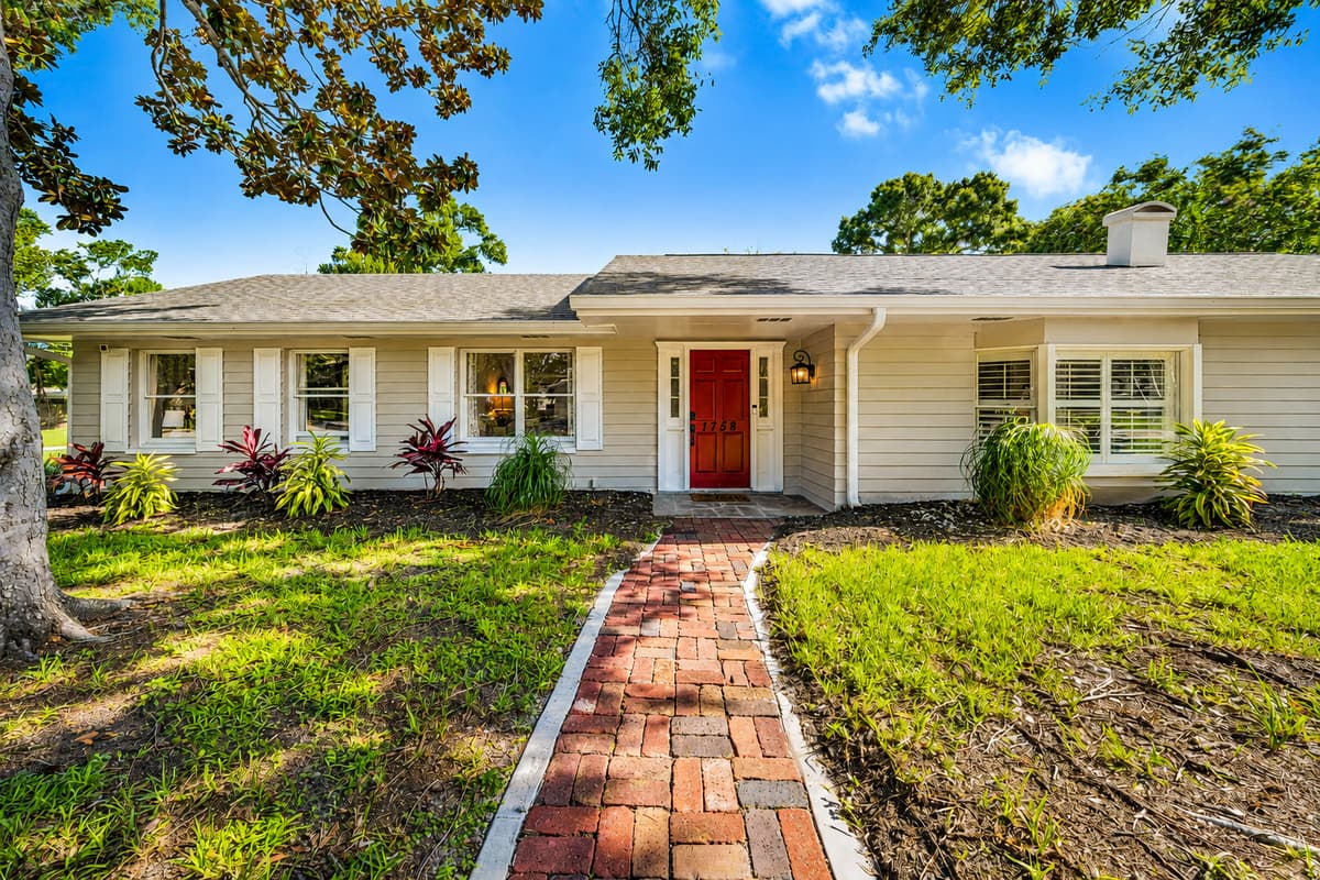 Brick path from the street to the door, lawn on both sides. The house sits back from the road, quiet.