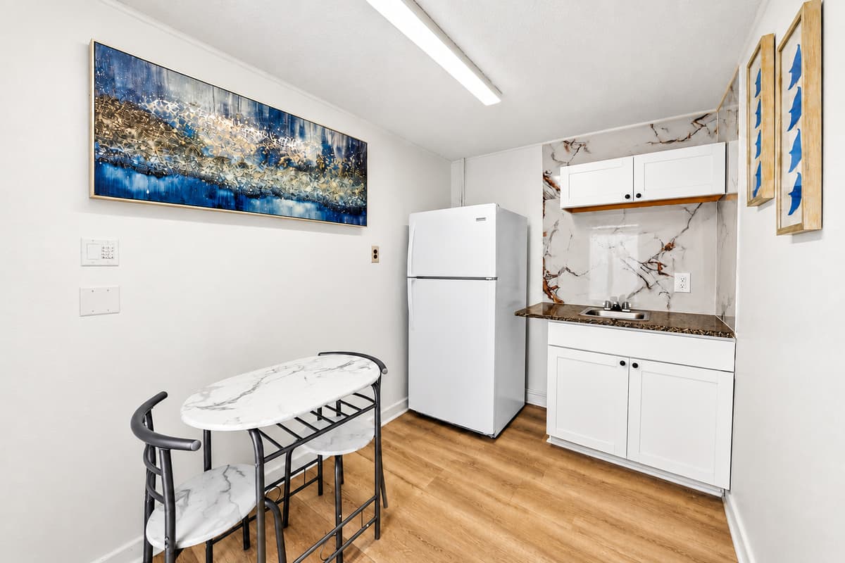 Cozy studio dining nook and kitchenette with refrigerator, sink, storage space, and seating for two, creating a private retreat within the property.