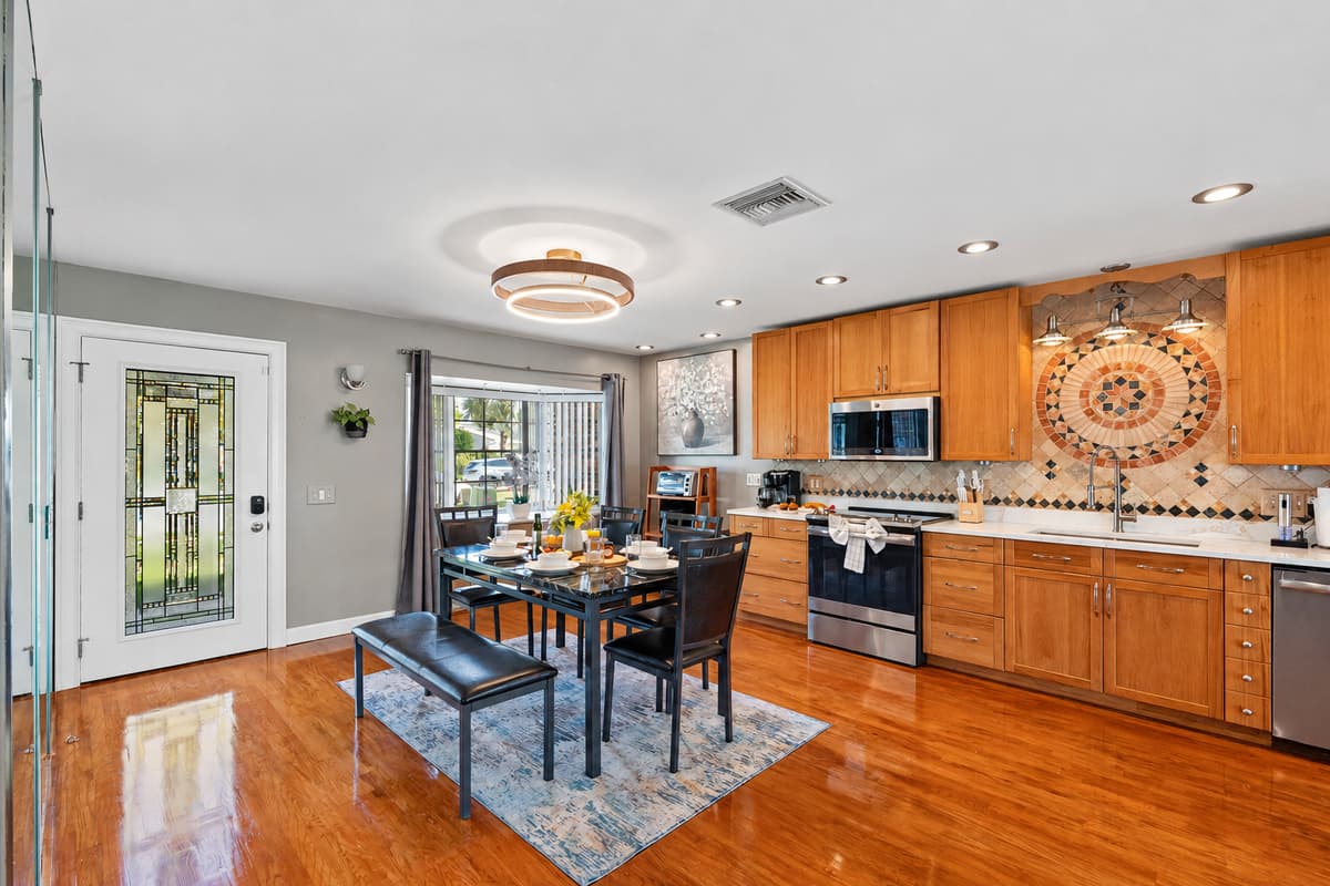 Soft recessed lighting and natural sunlight fill the room, highlighting the warm wood tones and gleaming countertops.