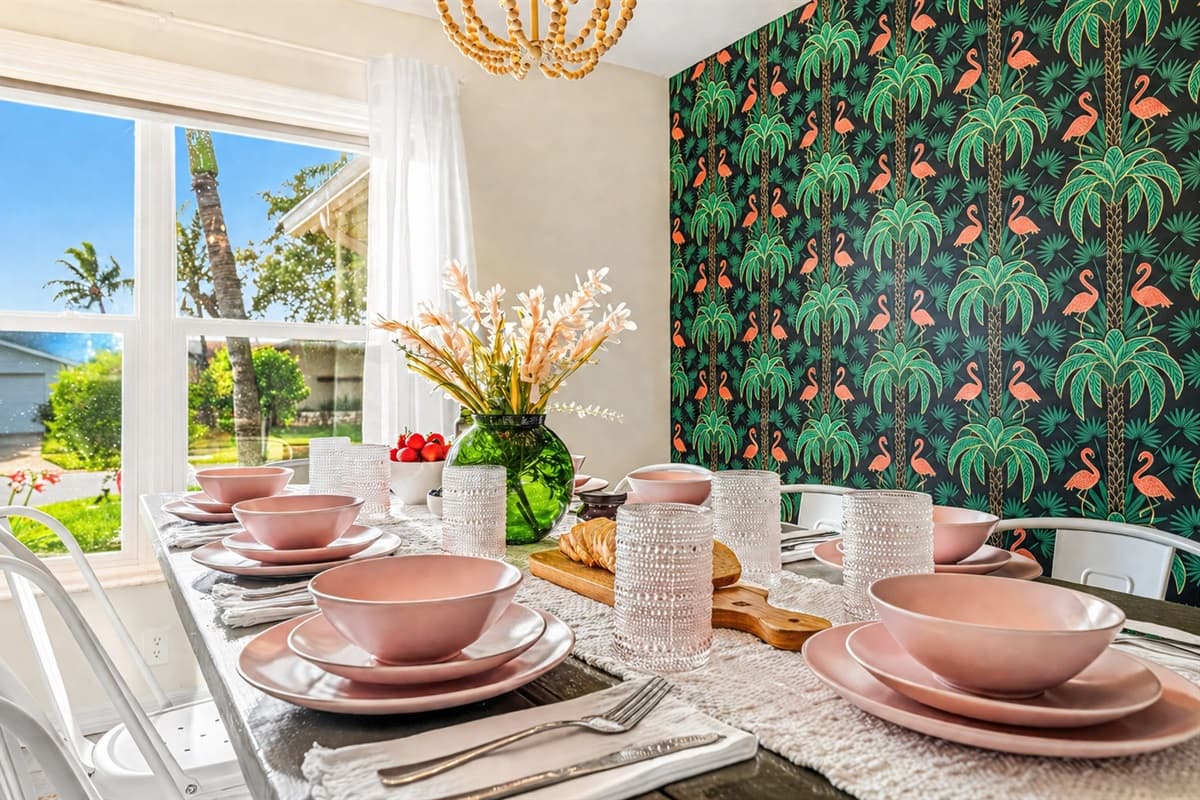 Beautifully styled dining table set by the window with natural light and tropical accent wall. (Table setting for staging purposes only)