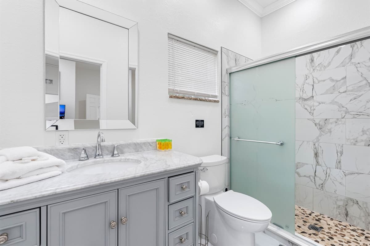 Bright, clean, and contemporary, the bathroom offers a spacious vanity with ample storage, a large mirror, and elegant finishes throughout.