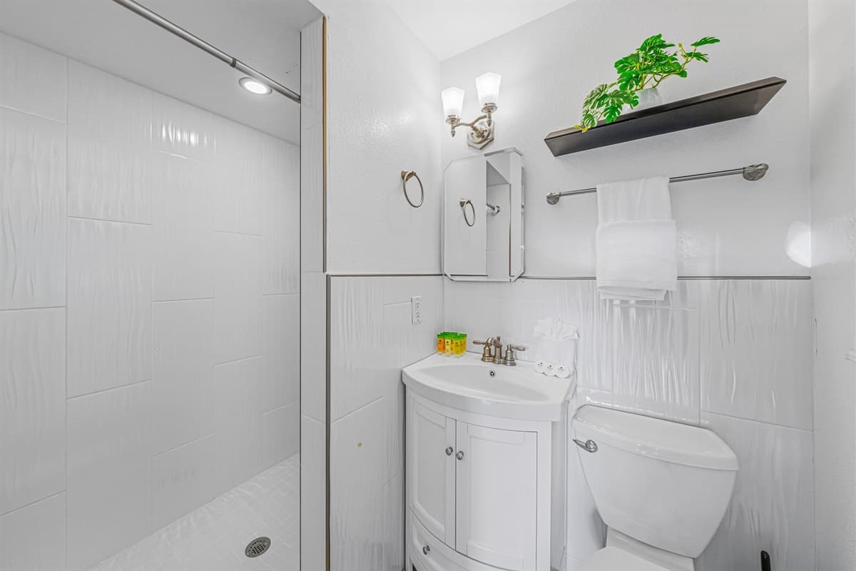Clean and modern bathroom with walk-in shower, fresh white finishes, and essential amenities 