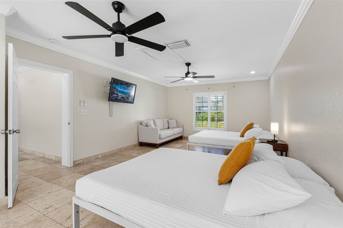 This bright and airy bedroom features two comfortable beds, a cozy sitting area, and a wall-mounted TV for ultimate relaxation.