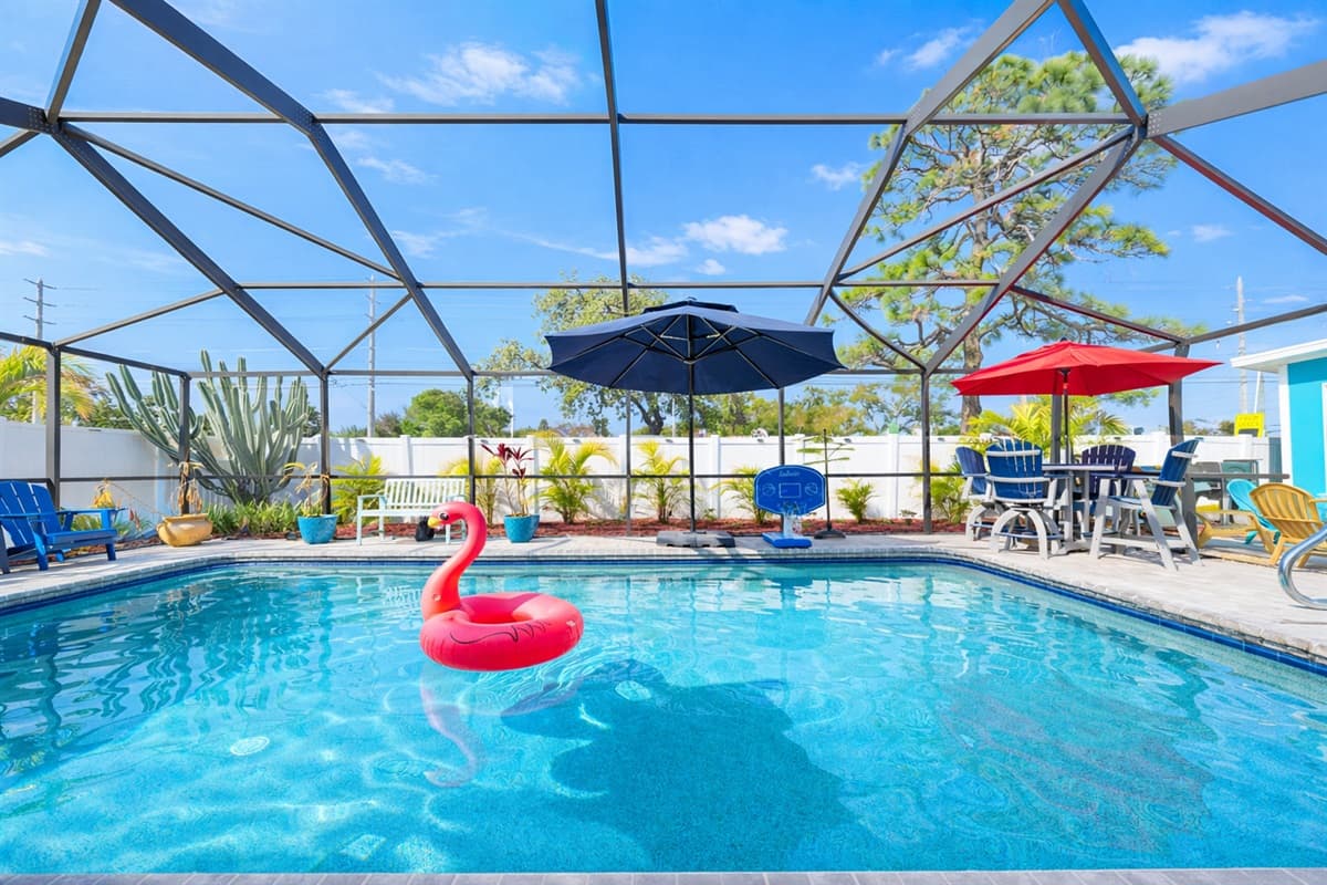 Sparkling blue pool surrounded by lounge chairs and tropical landscaping.