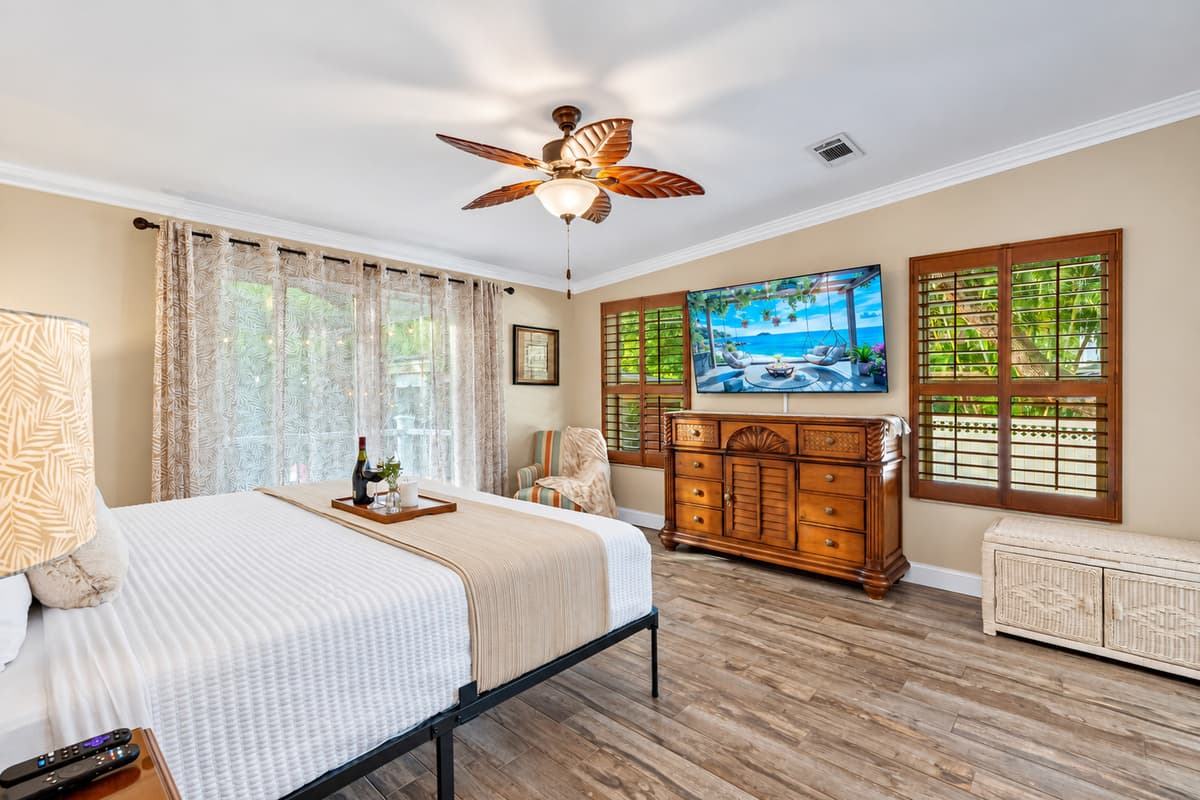 The master suite boasts a resort-like atmosphere with wood accents, large windows, and a peaceful view of the outdoor greenery.