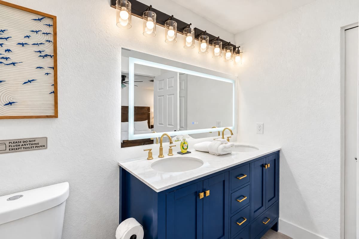 Bedroom 1 - Ensuite: Indulge in spa-like luxury with this beautifully designed bathroom featuring a dual-sink vanity, LED mirror, and rainfall shower surrounded by marble-style tile.
