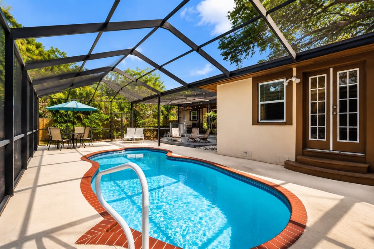 Scenic poolside view featuring outdoor seating, dining space, and a private resort-style atmosphere.