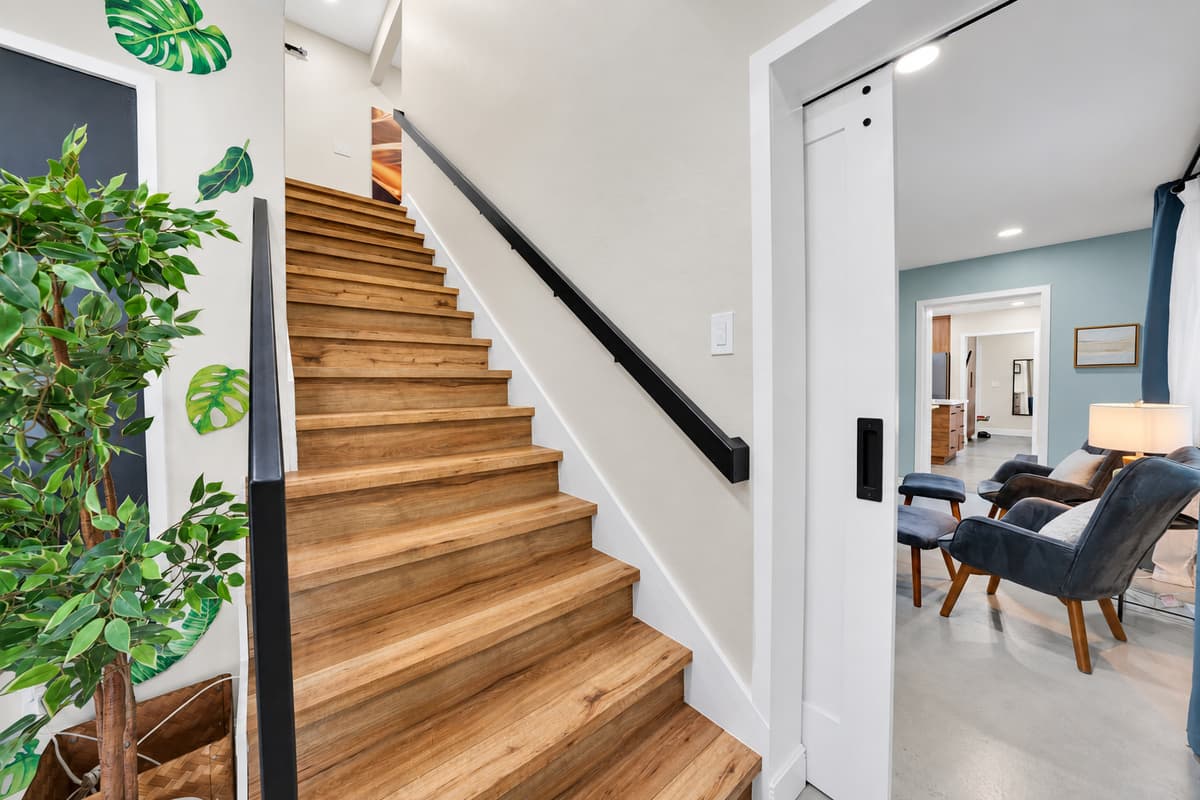 Two floors means two schedules. The stairs that separate the late crowd from the early risers, with the living areas open and bright at the bottom of them.