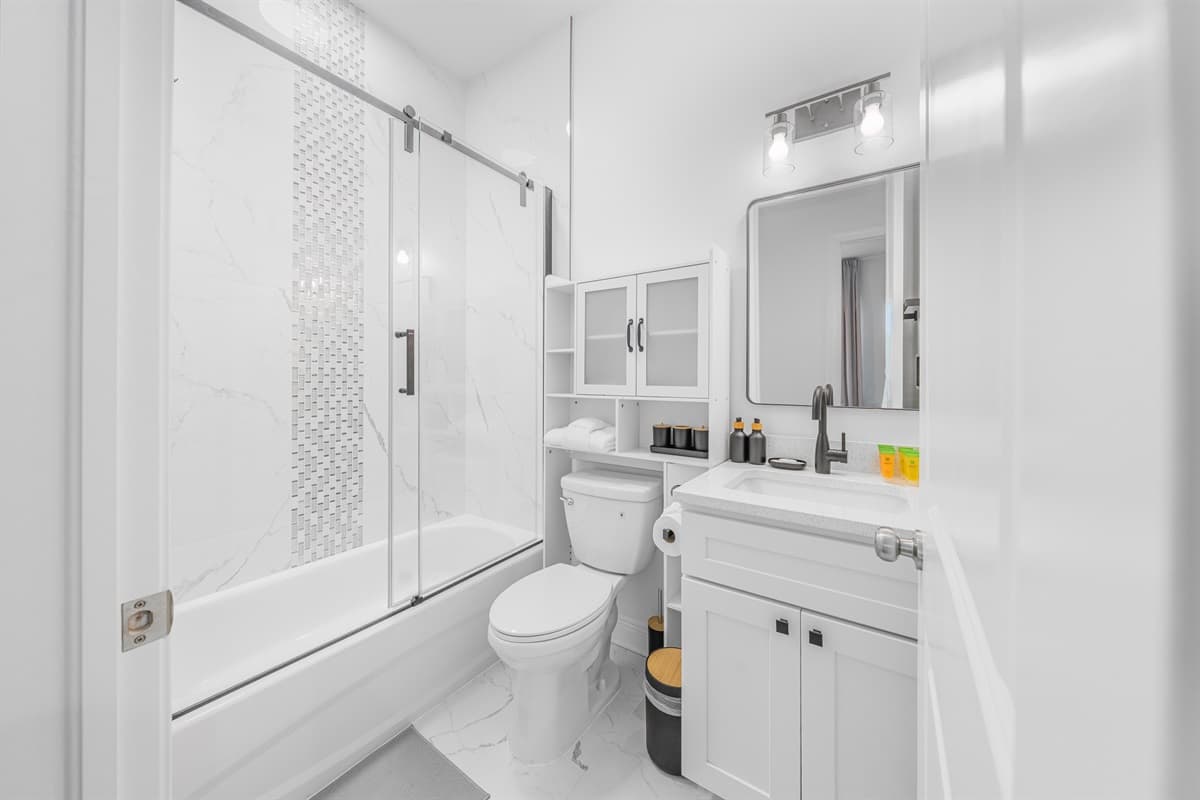 Bright bathroom featuring a shower/tub combination and well-lit vanity area.