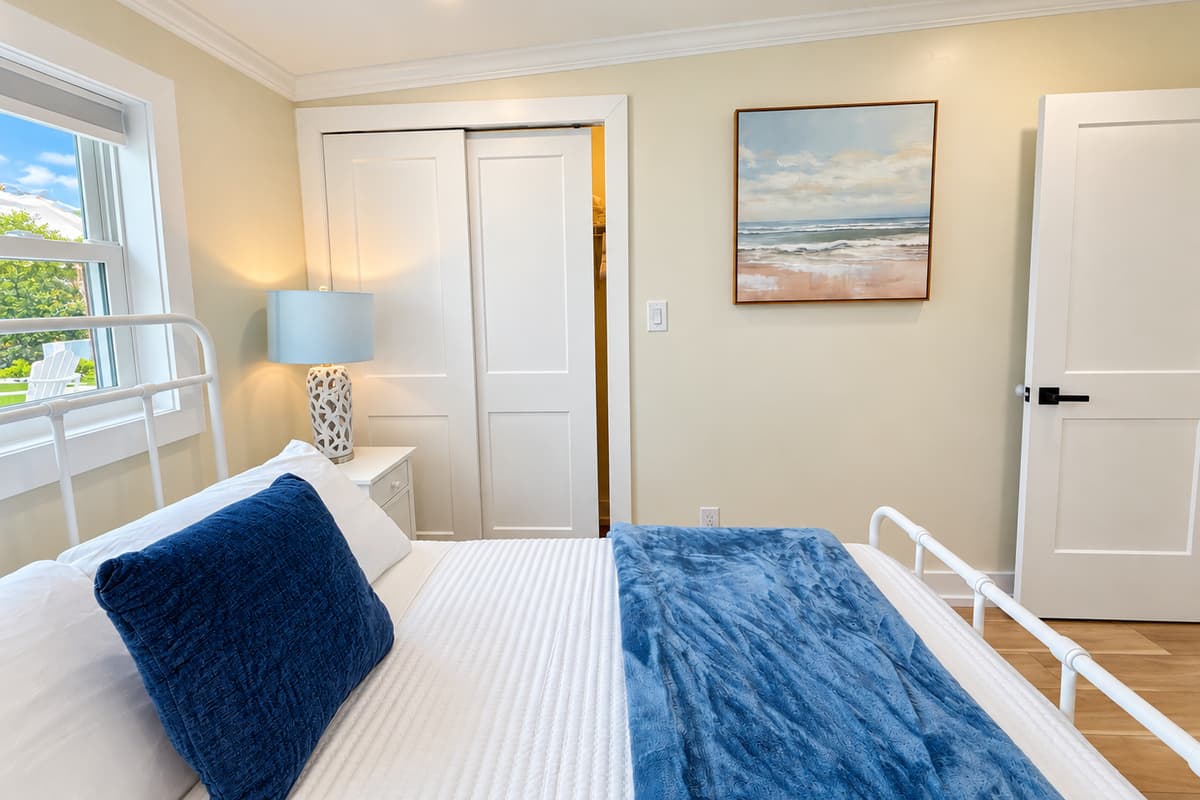 Queen bedroom with a white metal bed frame and smart TV.