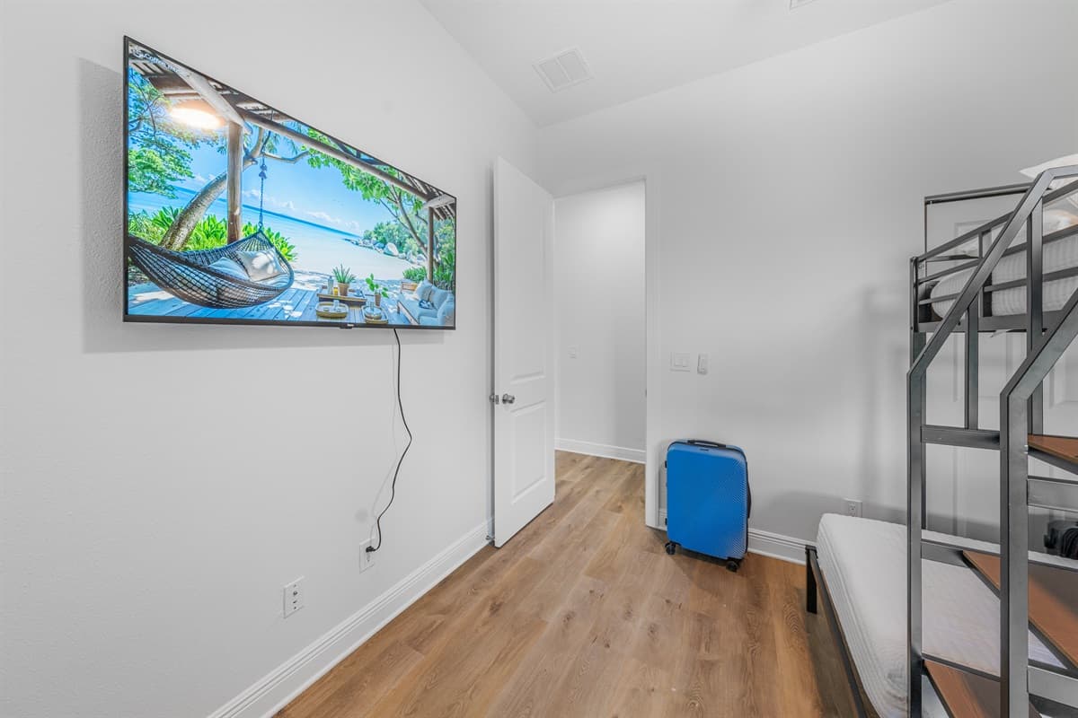 Bunk room with wall-mounted TV and open floor space, ideal for relaxing and entertainment.
