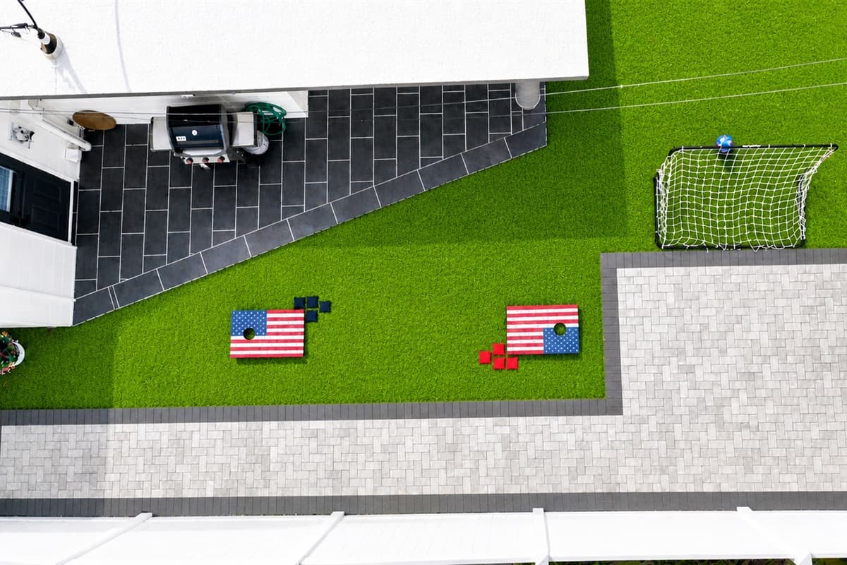 Top-down aerial shot of the backyard entertainment area with lawn games and patio.