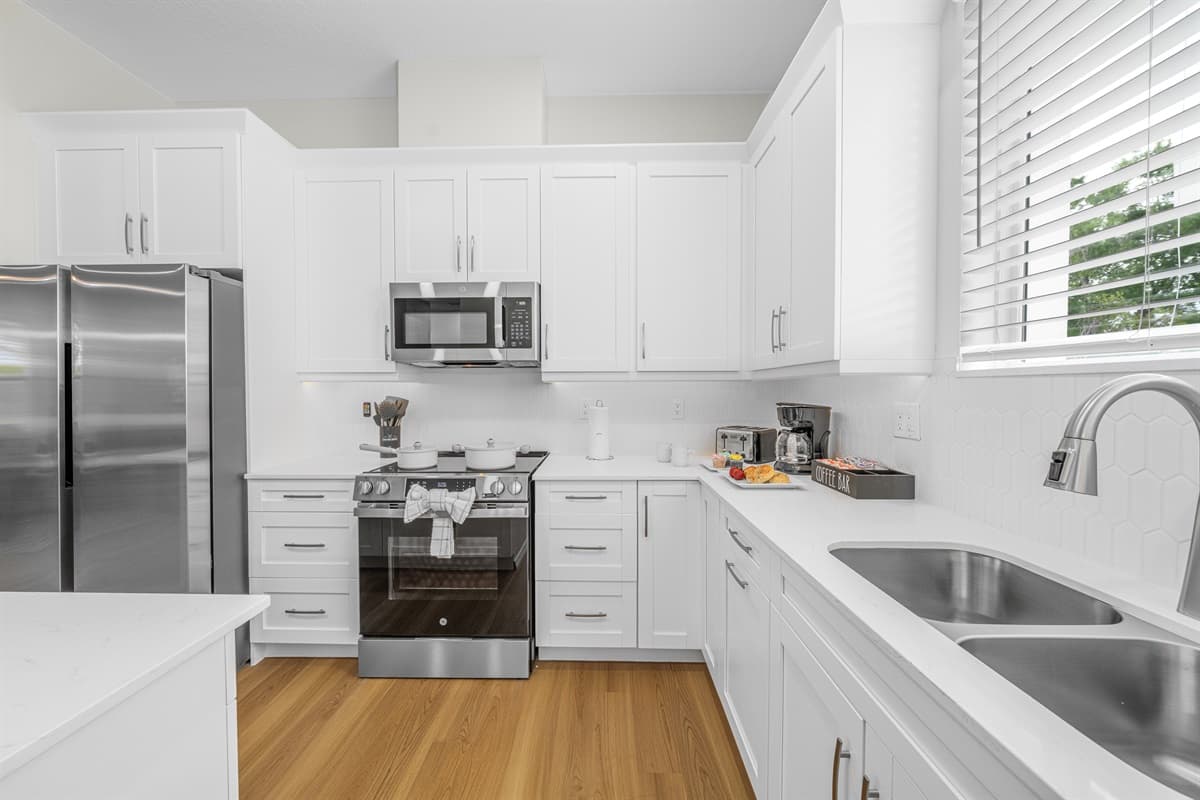 Modern, fully equipped kitchen featuring stainless steel appliances, bright cabinetry, and plenty of space for cooking and meal prep.
