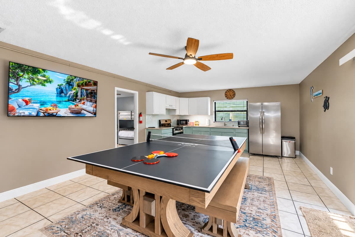 At the center of the room is a modern farmhouse-style table that transforms effortlessly from a dining space to a full-size ping pong table.