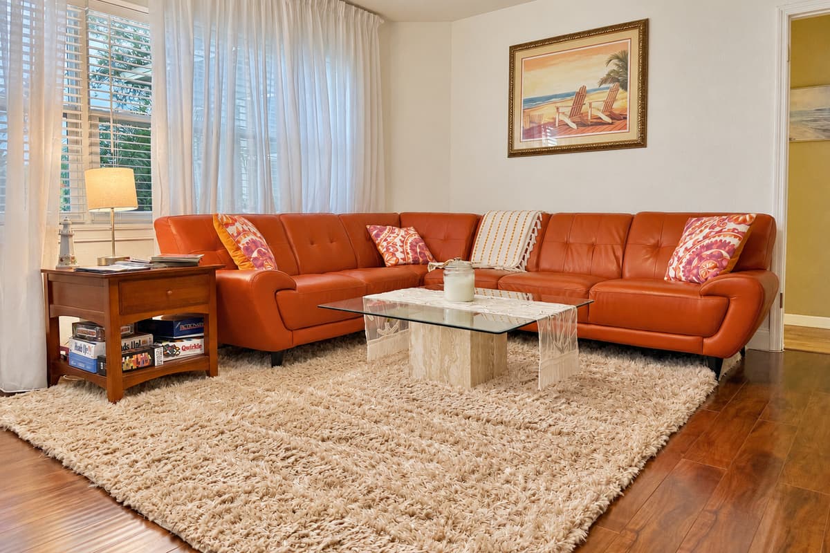 Kick back on the plush leather sectional surrounded by soft textures, coastal art, and natural light streaming through sheer curtains.