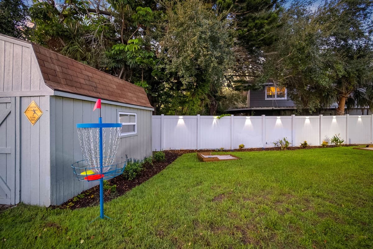 This backyard is designed for both relaxation and play, featuring a hammock, firepit lounge, disc golf, and cornhole setup — great for families or group getaways.