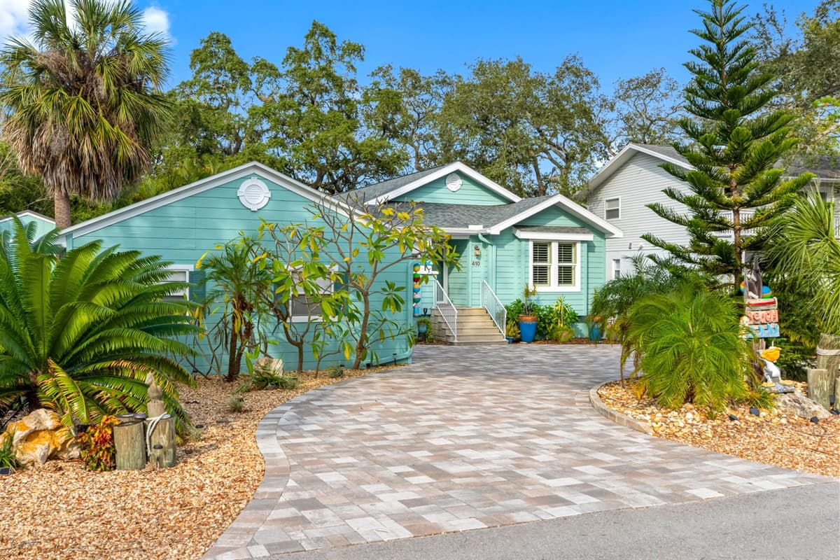 A welcoming cottage façade with fresh coastal colors, stylish white trim, and a spacious paver driveway.