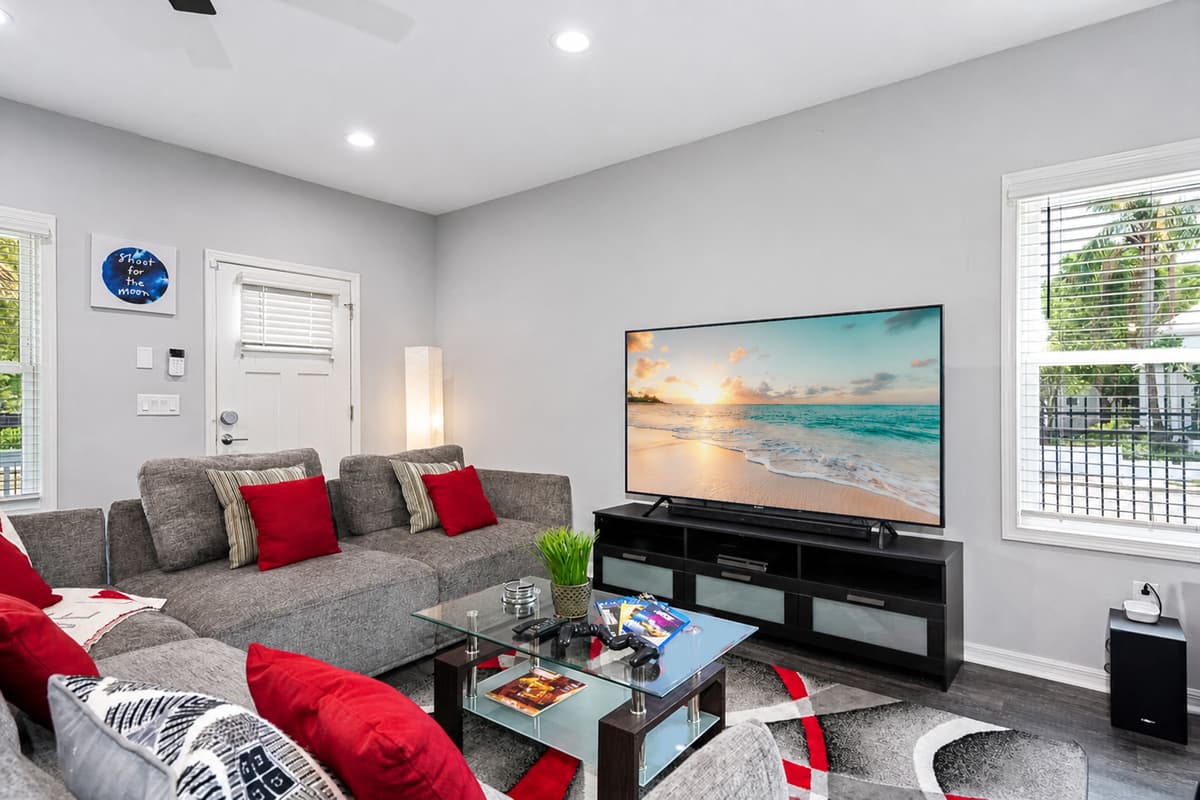 The grey pillows add a touch of sophistication and balance, while the pops of red inject a vibrant energy into the space, creating a visually captivating contrast.
