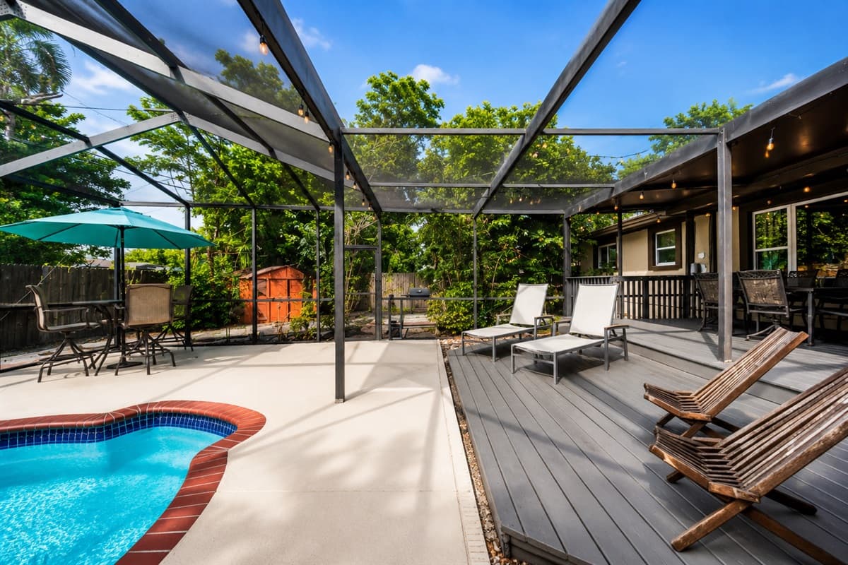 Spacious pool deck featuring comfortable lounge chairs, shaded seating, and beautiful backyard views.