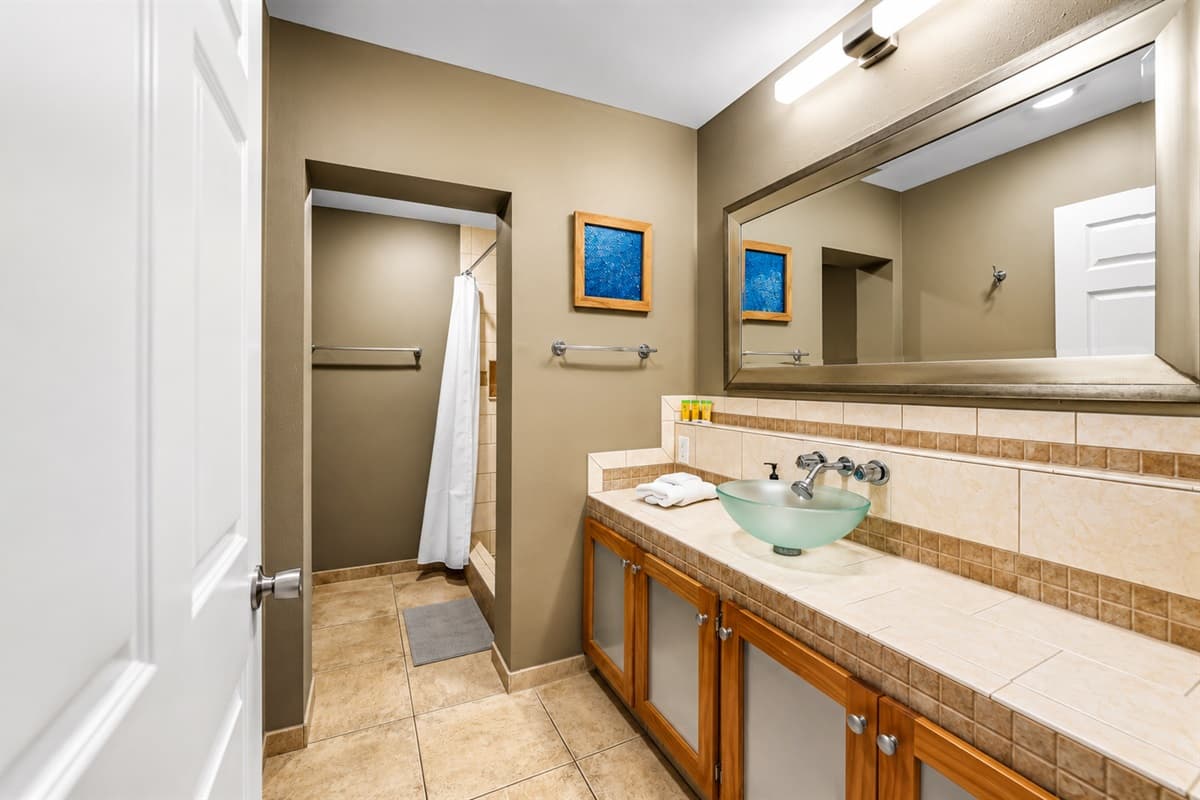 Bright and functional bathroom with a modern glass vessel sink, large mirror, and ample counter space.