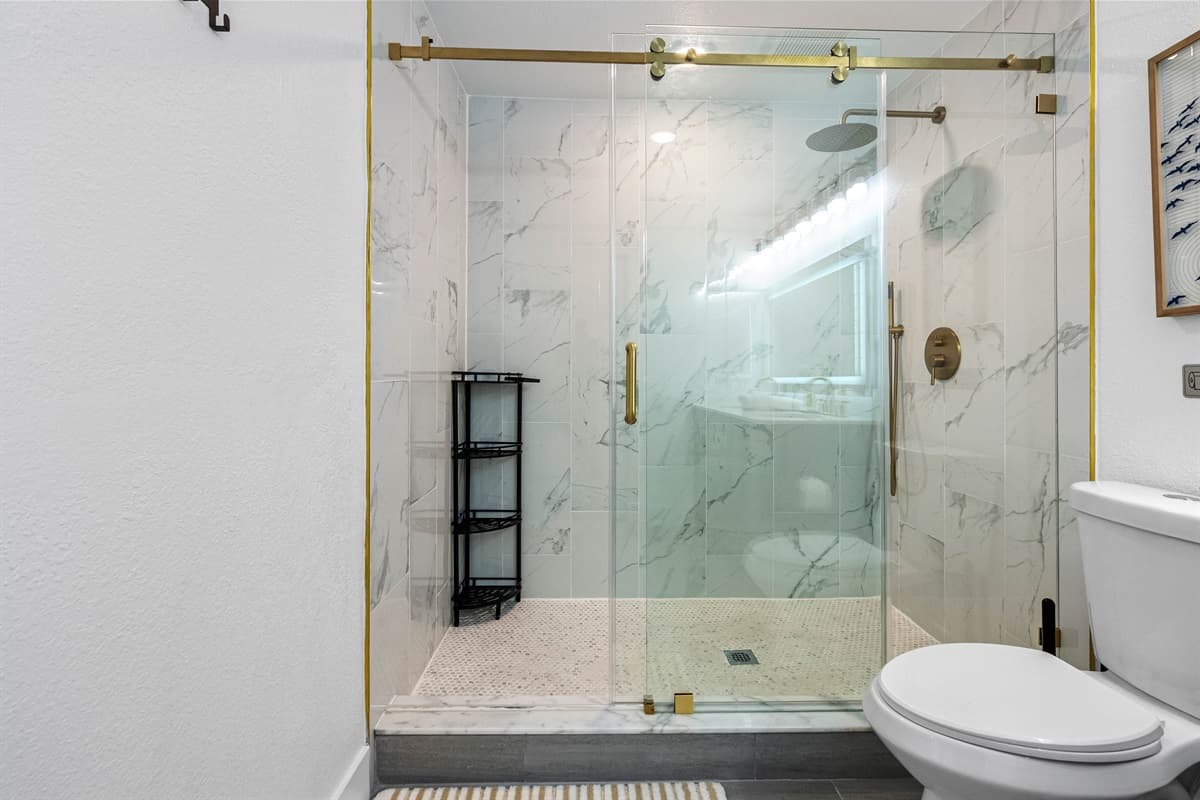 Bedroom 1 - Ensuite: This elegant bathroom includes a backlit mirror, luxe gold accents, and a spacious shower perfect for unwinding.
