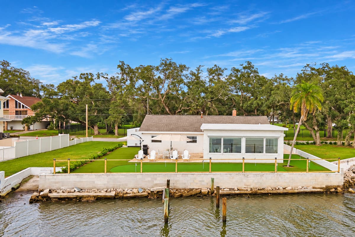 A backyard that ends at the water. The patio and putting green run right up to the seawall and dock posts. Wide green space, open sky and the bay as your only neighbor out back.