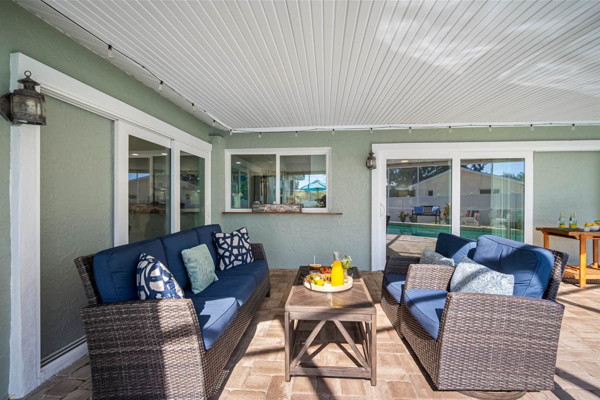 Enjoy the best of indoor-outdoor living with this screened pool and cozy lounge area, surrounded by tropical plants and twinkling string lights.