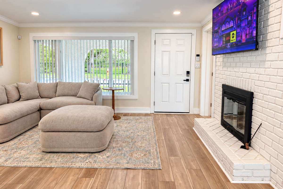 Front living room with sectional seating, TV and fireplace feature.