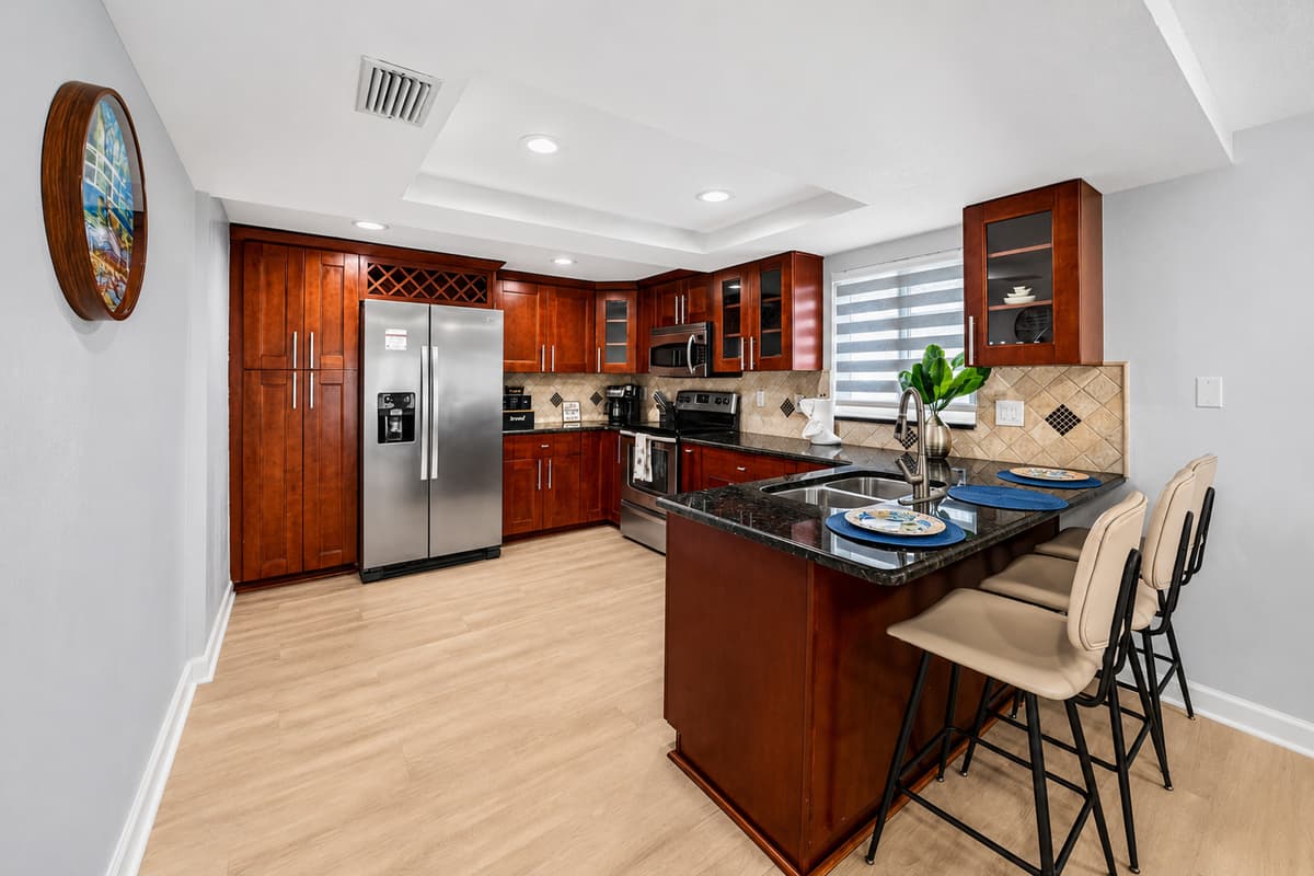 Fully equipped kitchen with stainless steel appliances, granite countertops, a breakfast bar, and ample space for preparing meals during your stay.