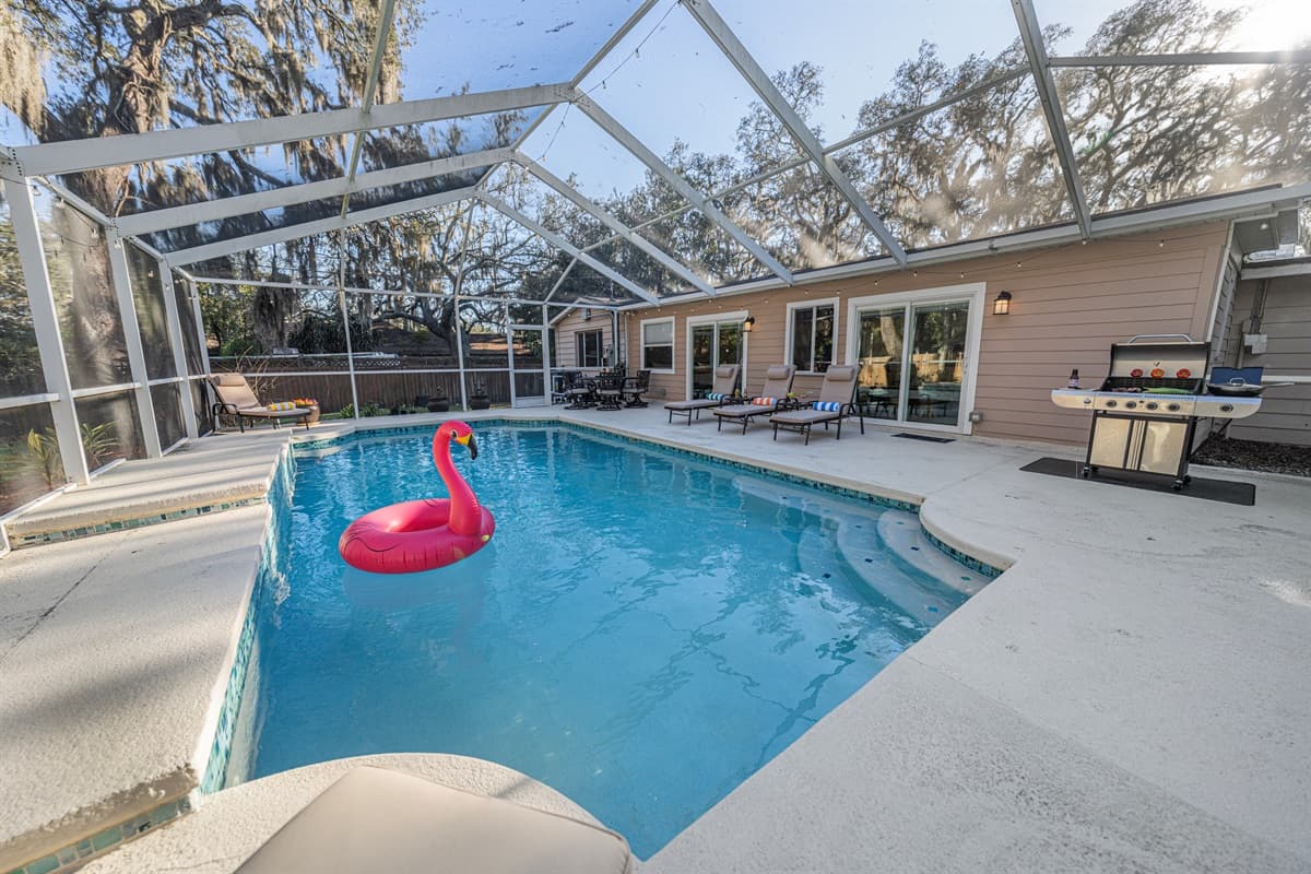 Another inviting angle of the pool showcasing the curved design, ample deck space, and comfortable loungers ideal for relaxing between swims.