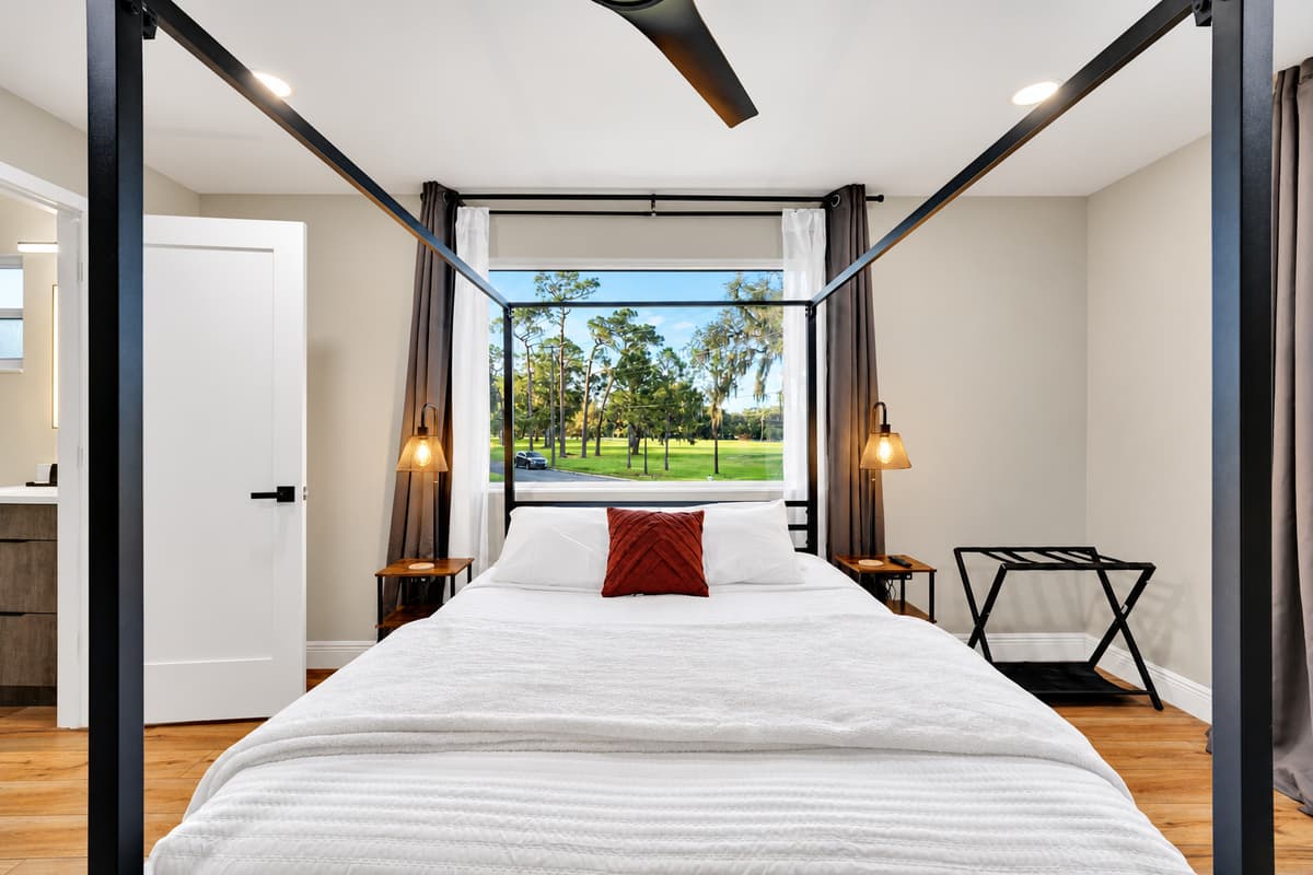 The view that decides which room you want. Tall four-poster bed, garden outside the window and light that arrives slowly. Coffee here first, then the pool before anyone's awake.