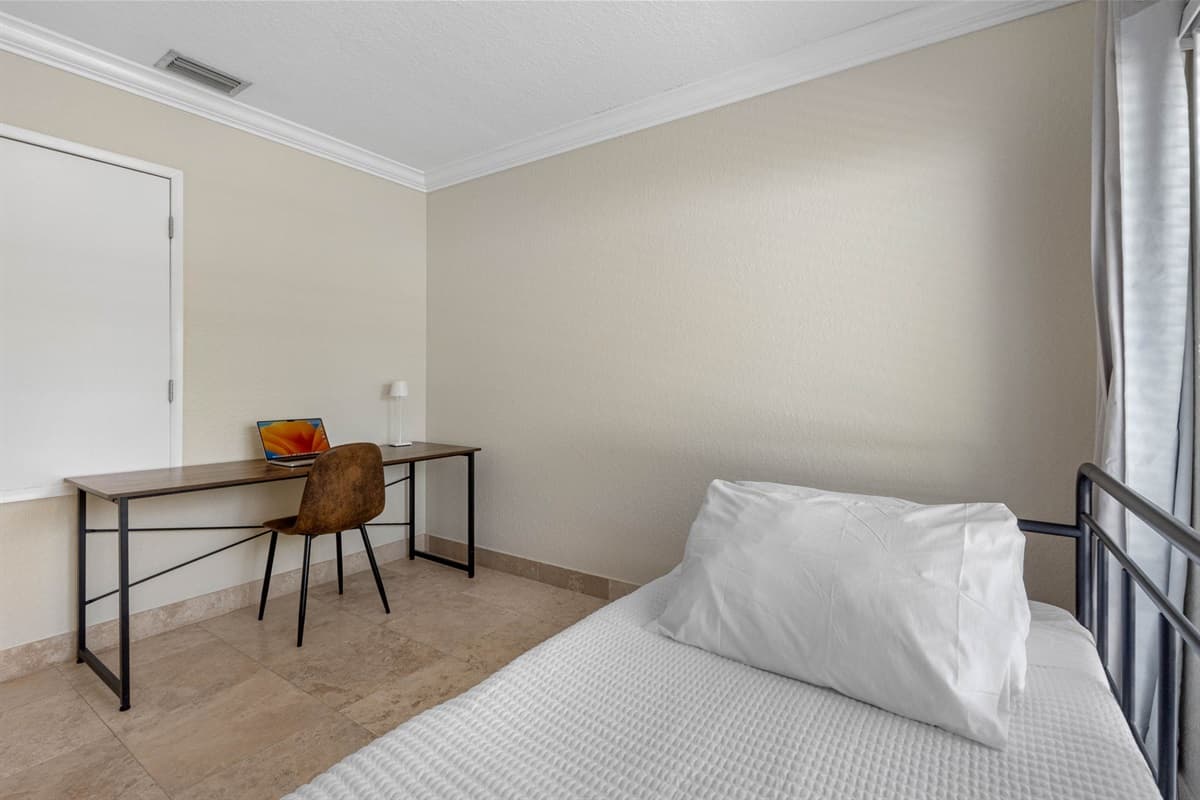A sunny room offering both a comfortable daybed and a dedicated work desk, ideal for remote work or study.