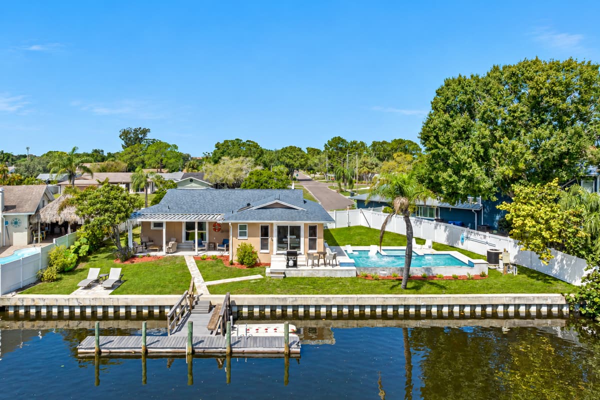 Aerial back view of the property showcasing the beautiful heated pool and access to dock in the lake. Don't miss the opportunity and book now!