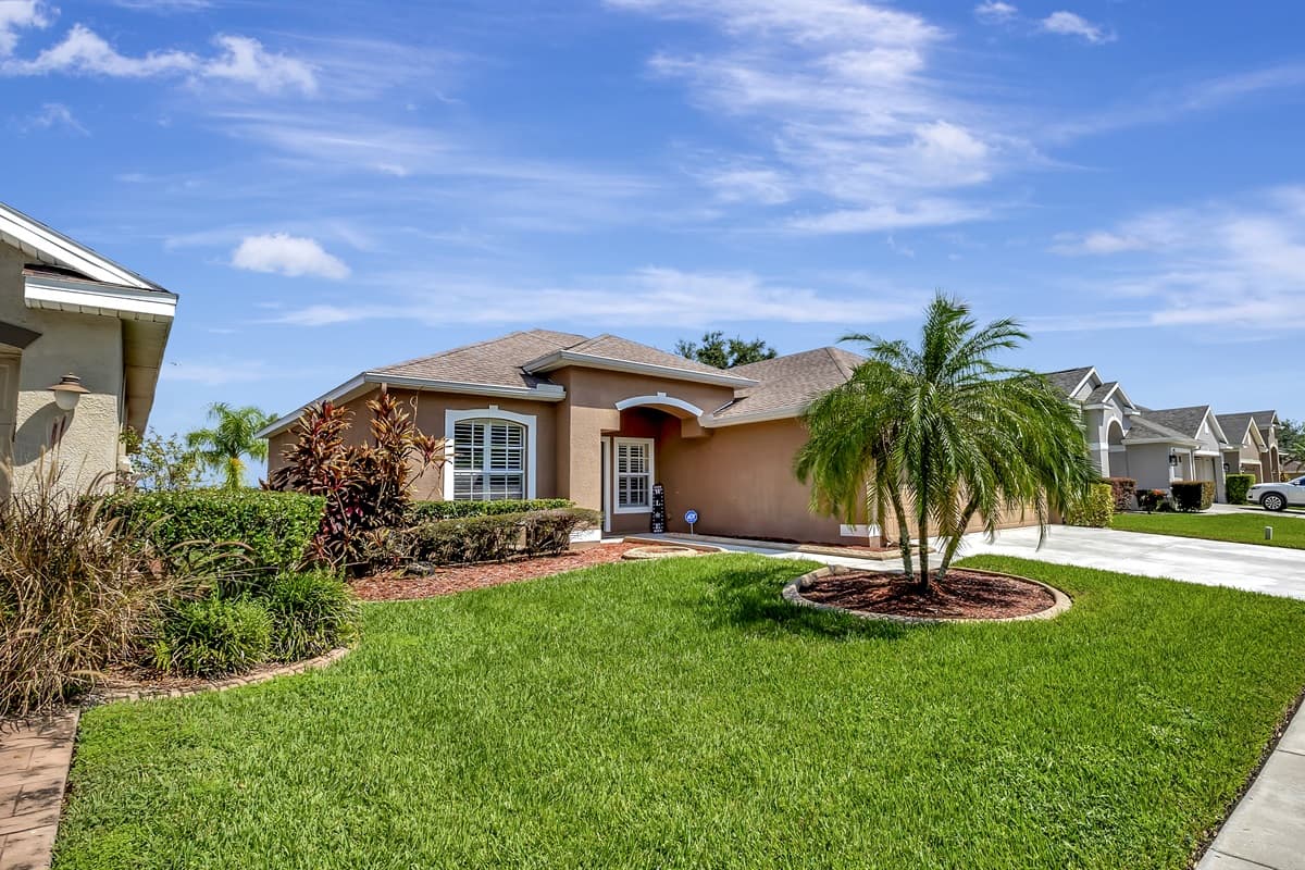 The stunning exterior of the home highlights a lush green front lawn and an exceptionally spacious driveway.