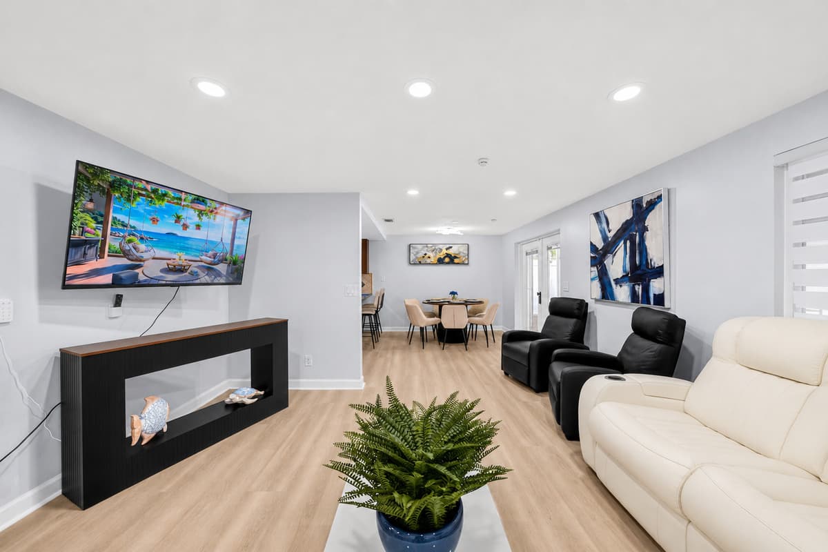 Modern living room with large flat-screen TV, comfortable reclining seating, and a stylish fireplace feature wall.