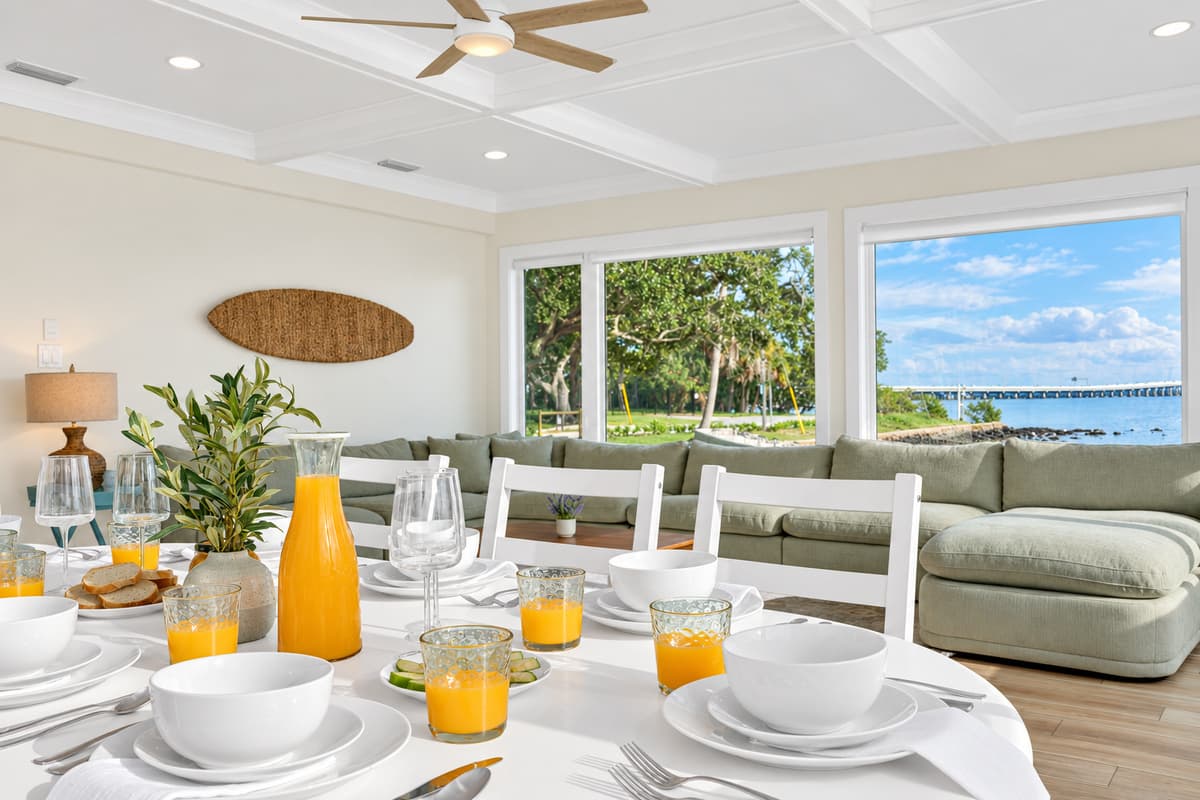 Brunch with a waterfront view. A table set with fresh juice and bowls, the sectional behind and the bay through the windows. A beautiful start to the day.