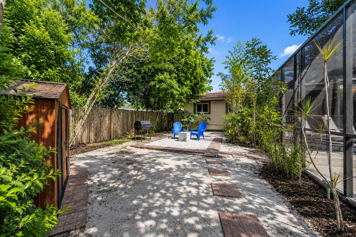 Peaceful garden-style backyard with shaded walking paths, outdoor seating, and private fenced surroundings.