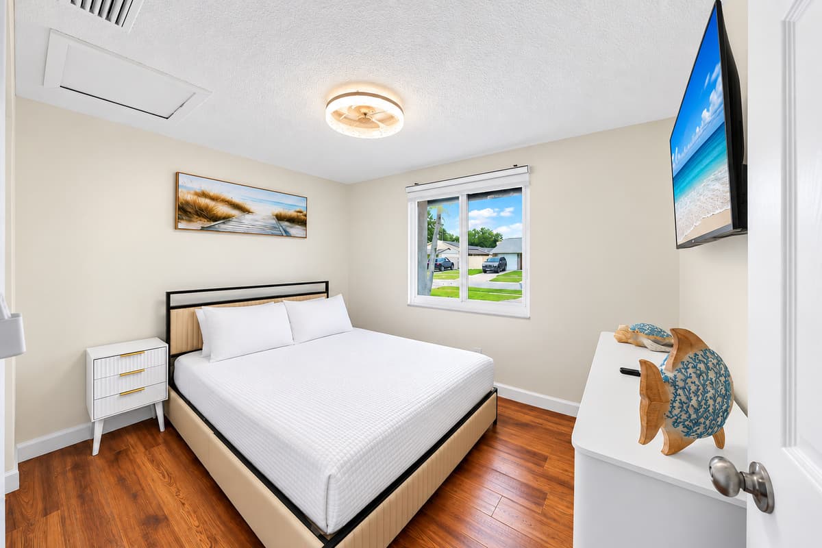Peaceful guest bedroom featuring a queen bed, Smart TV, and large windows that fill the room with natural light.
