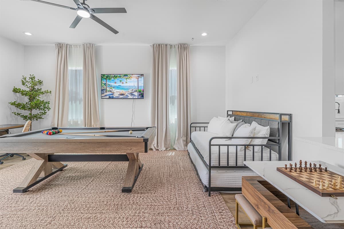 Spacious game room featuring a pool table, cozy seating area, and large windows that fill the space with natural light.